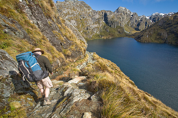 Tramper sidling around Lake Harris on the Routeburn Track